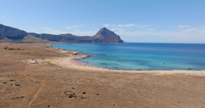 Aerial view of Macari Beach, located near San Vito Lo Capo in Sicily, Italy. In the background is a mountain called Monte Cofano, and the turquoise sea in the foreground.