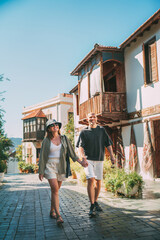 Fototapeta premium Middle aged couple walking hand in hand along narrow street in Kas town historical center. Romantic travel, love relationship, honeymoon vacation and happy retirement lifestyle concept.