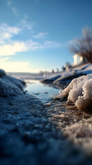 Winter landscape features melting snow and ice by the lakeside with clear blue sky
