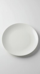 Fototapeta premium Plain white circular ceramic dish rests against a bright, neutral background