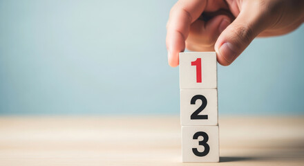 Hand placing number one block on a stack of numbers one two three