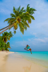 Tranquil closeup calm sea water waves with palm trees. Woman tourist swinging, Tropical island beach landscape exotic shore coast. Summer vacation, holiday amazing nature. Relax paradise, Maldives.