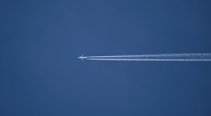Airplane flying in blue sky leaving contrail