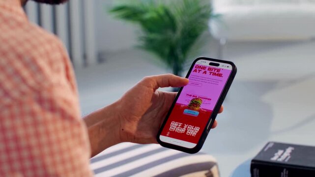 Close-up 4K Ultra HD footage of hands browsing a fast food burger website on a smartphone, showing mobile ordering, online food delivery, and digital consumer experience.