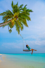 Tranquil closeup calm sea water waves with palm trees. Woman tourist swinging, Tropical island beach landscape exotic shore coast. Summer vacation, holiday amazing nature. Relax paradise, Maldives.