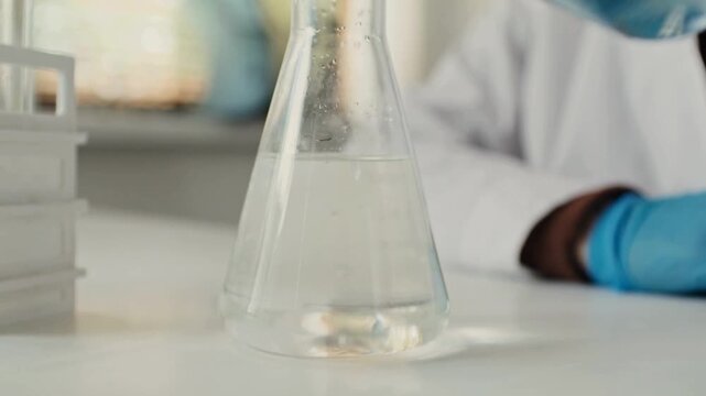 Close-up 4K Ultra HD footage of liquid mixing in a flask demonstrating a precipitation reaction in a laboratory, showing chemical formation, fluid motion, and scientific experiment process.