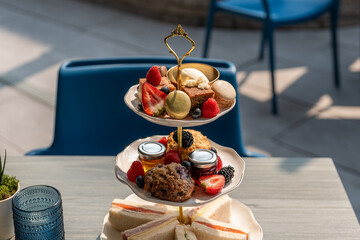 Elegant tiered platter with assorted pastries and fruits served during afternoon tea in a bright cafe setting