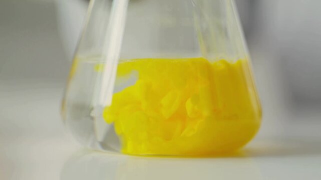 Close-up 4K Ultra HD footage of liquid mixing in a flask demonstrating a precipitation reaction in a laboratory, showing chemical formation, fluid motion, and scientific experiment process.