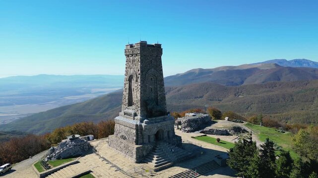 Impressive stone monument standing on a mountain peak surrounded by an autumnal landscape