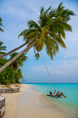 Tranquil closeup calm sea water waves with palm trees. Man tourist swinging, Tropical island beach landscape exotic shore coast. Summer vacation, holiday amazing nature. Relax paradise, Maldives.