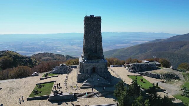 Aerial view flying away from the Shipka Monument of Liberty revealing the surrounding landscape