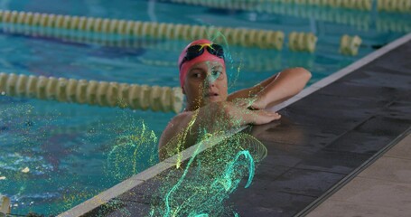 Swimmer wearing pink cap holding lane edge in lap pool, with green particles, copy space