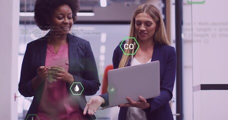 Walking coworkers holding coffee mug analyzing on laptop in office, with overlay CO2 droplet icons