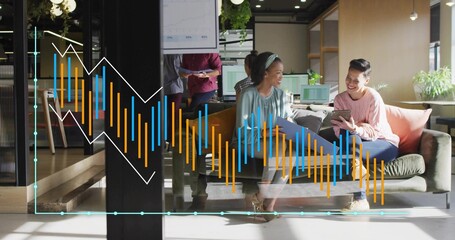 Collaborating team seated on grey sofa in open-plan office lounge, holding laptop tablet and folder