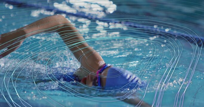 Swimming female swimmer performing front crawl in competition pool, wearing purple cap and goggles