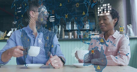 Colleagues in business casual analyzing digital world map overlay in cafe, holding coffee mugs
