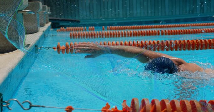 Swimming adult male performing front crawl in marked pool lane, with swim cap and orange dividers - Powered by Adobe