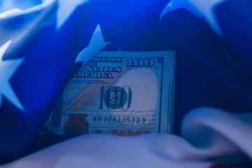 United States currency partially concealed by an American flag illustrating patriotism and financial themes