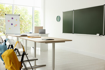 Fototapeta premium Green chalkboard and stylish furniture in classroom. Mockup for design