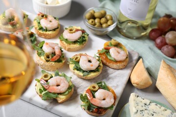 Delicious bruschettas with shrimps and wine on light table, selective focus