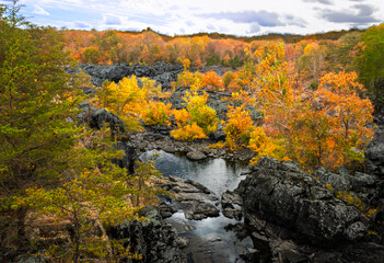 Low water in a channel of the potomac river at great falls surrounded by trees blazing with the colors of autumn