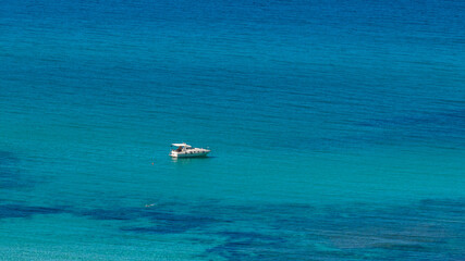 Aerial view of a single motorboat isolated in crystal clear turquoise sea. Holidays and boat trips concept.