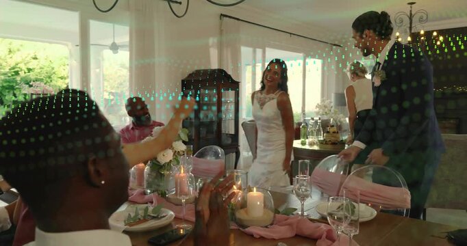 Senior guest handing bouquet leading bride and groom to wedding reception table, guests applauding