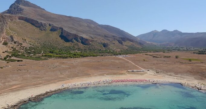 Aerial view of Macari Beach, located near San Vito Lo Capo, in province of Trapani, in Sicily, Italy. In the background is a mountain and the turquoise sea in the foreground.