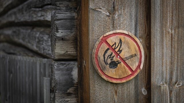 Runde Holztafel mit aufgemaltem Verbotssymbol gegen das Entfachen von Feuer, historischer Bauernhof und Pilgerunterkunft Budsjord, Dovre, Pilgerweg Olavsweg oder Olavsleden, Gudbrandsdalen oder Gudbrandstal, Norwegen