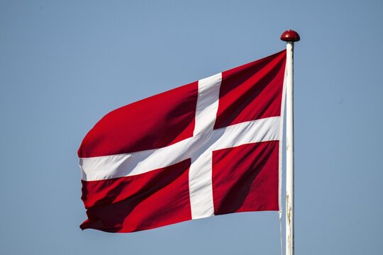 Danish flag on flagpole waving in the wind, Ringk&oslash;bing Fjord, Denmark