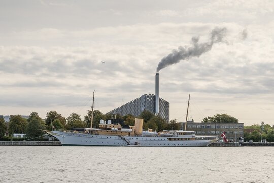 The Danish royal yacht or yacht Dannebrog, in the background waste incineration plant CopenHill or Amager Bakke with ski slope and tow lift on the roof, Christianshavn, Copenhagen, Denmark