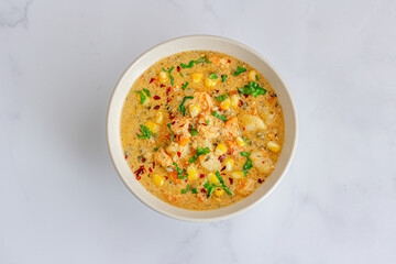 Creamy seafood chowder made with fresh shrimp, sweet corn, potatoes, garnished with herbs and cracked pepper
