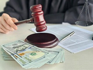 Courtroom scene with a judge's gavel beside cash and legal documents during a trial in a modern...
