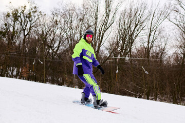 Bearded man joyfully snowboarding down a snowy slope in vibrant winter gear