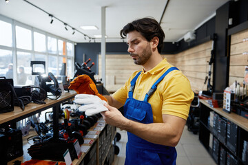 Male young worker holds two pairs of gloves