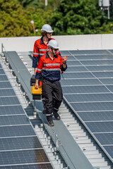 Solar engineer teamwork rooftop maintenance checks energy systems bright sun, two workers safety gear walk along panel array with toolkit, focus inspection process and efficient power flow