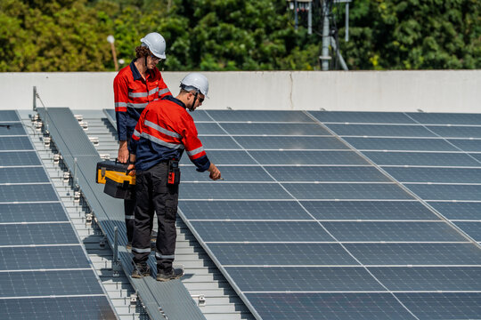 Solar engineer teamwork maintenance energy rooftop array, two workers safety helmet inspect panel sunlight, careful repair boosts clean power and grid supply with steady focus and professional calm
