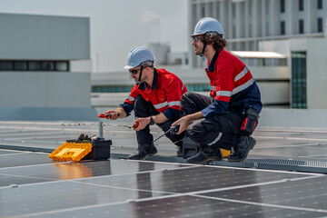 Solar engineer teamwork maintenance energy rooftop inspection under bright daylight, two technician crouch on panel with tool box, safety helmet and glove show careful work and calm focus