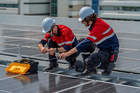 Solar engineer teamwork on rooftop maintenance ensures energy flow with careful repair under bright daylight and safety gear support