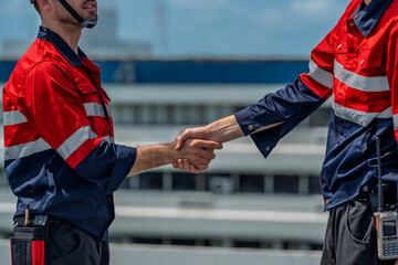 Confident solar engineer handshake shows teamwork during maintenance on site, bright energy goal under clear sky encouraging progress and trust between colleagues