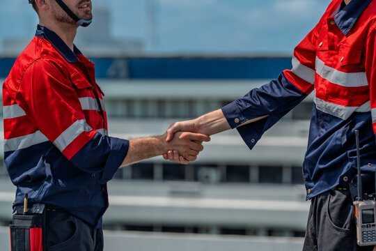 Confident solar engineer handshake shows teamwork during maintenance on site, bright energy goal under clear sky encouraging progress and trust between colleagues
