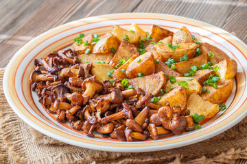 Fried potatoes chanterelle mushrooms seasoned paprika rustic wooden table plate