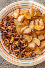 Fried potatoes chanterelle mushrooms seasoned paprika rustic wooden table plate