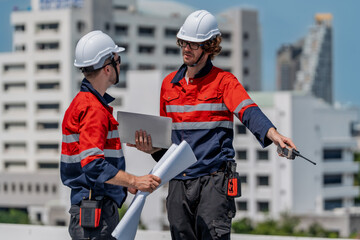 Engineer teamwork maintenance energy solar site planning under bright sky on rooftop with hard hat and safety uniform, focused discussion builds confidence and progress for clean power project