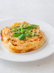 Circular lasagna presentation topped with fresh arugula served on elegant white plate