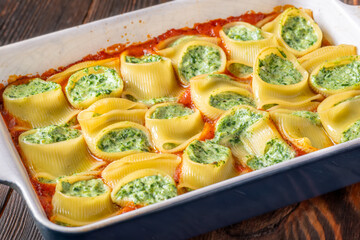 Golden baked lumaconi filled with ricotta and spinach resting in rich tomato sauce