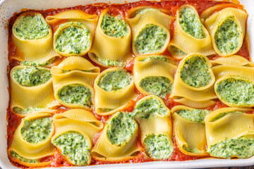 Golden baked lumaconi filled with ricotta and spinach resting in rich tomato sauce