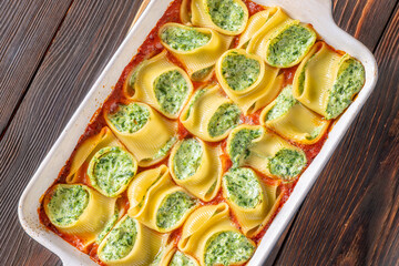 Golden baked lumaconi filled with ricotta and spinach resting in rich tomato sauce