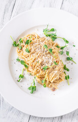 Creamy traditional carbonara served with grated parmesan on smooth white ceramic plate