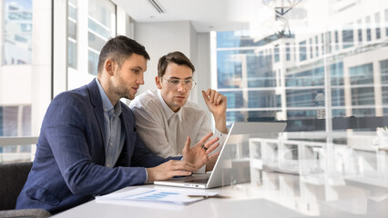 Confident young business partners working on online project solutions together